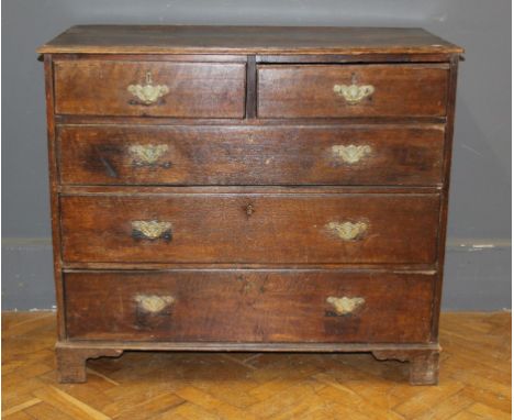 A George III oak chest of two short and three long drawers with florally engraved batswing brass handles, on bracket feet, 10