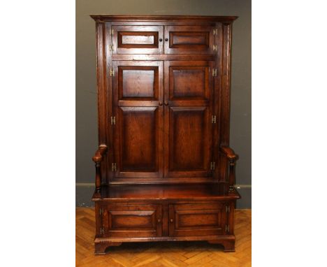 A Titchmarsh and Goodwin oak high back settle, fitted three pairs of fielded panel doors, on bracket feet. 187 x 114 x 61cm