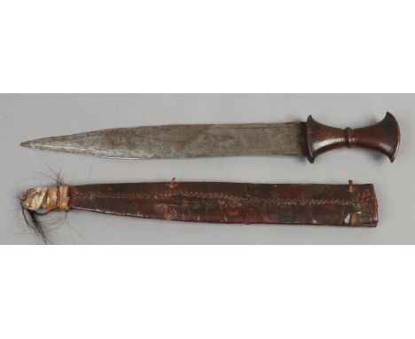 A tribal short sword with carved hardwood grip and leather mounted scabbard, possibly Ethiopian. Blade length 41.5cm. Conditi