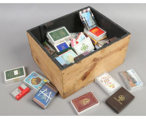 A wooden box and contents of packs of playing cards including tourist examples.