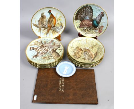 A full set of twelve Franklin porcelain game birds of the world cabinet plates by Basil Ede with books and papers.