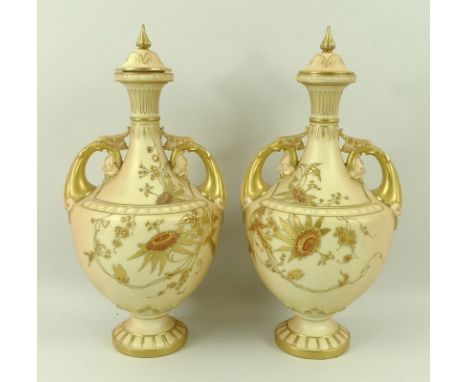 A pair of Royal Worcester blush ivory vases and covers, of small gourd form, on pedestal bases, the handles modelled with mas