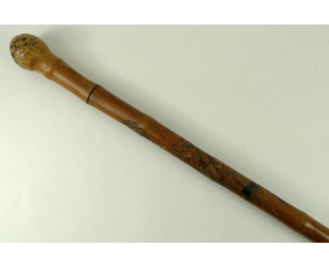 A Japanese sword stick, carved with a warrior killing a snake to the shaft and a root ball knop, 92cm. 