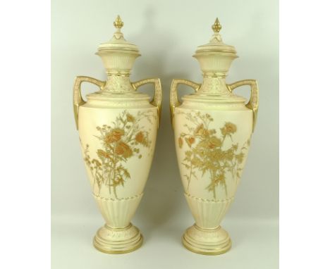 A pair of Royal Worcester blush ivory twin handled vases and covers, decorated with thistles in high relief in the Japanese s