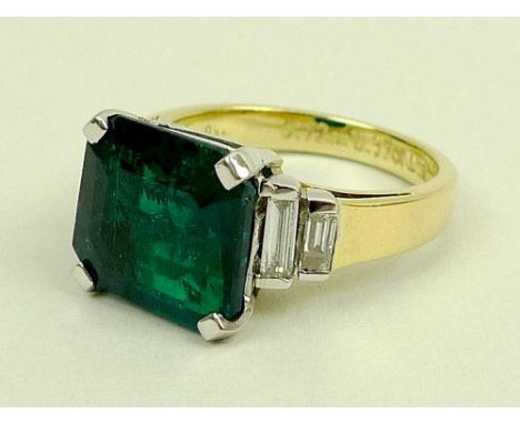 An 18ct gold, emerald and diamond dress ring, the central square cut emerald of 5.72ct, 11 by 12mm, flanked by two baguette c