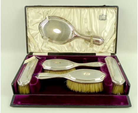 A George V silver vanity set, in fully fitted velvet lined case, comprising hand mirror, and two pairs of brushes, (missing c