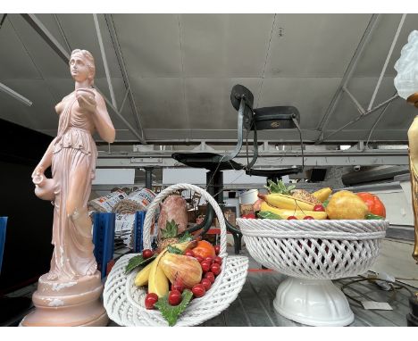 Two large ceramic fruit bowls with various fruits and a figure of a lady. 