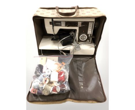 A Jones electric sewing machine with lead and pedal, roll of floral upholsterer's fabric, spools of thread, fabric light shad