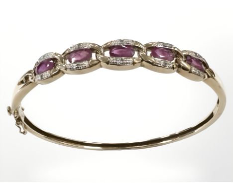 A 9ct yellow gold diamond and ruby bangle, 58 mm x 52 mm internal diameter, 12.2g.