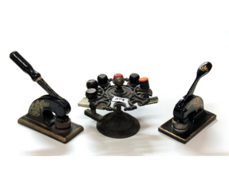 A 19th century cast iron stand with a collection of stamps and two lever stamps.