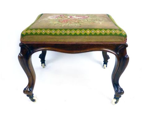A Victorian walnut and floral tapestry upholstered stool, with carved cabriole legs terminating in white ceramic casters, h. 