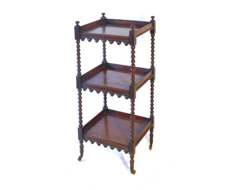 A Regency mahogany three tier whatnot, with bobbin turned supports and arched aprons to each shelf, with brass cup ceramic ca