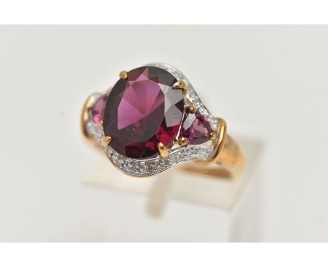 A 9CT GOLD GARNET AND DIAMOND DRESS RING, centring on an oval cut garnet, four claw set, flanked by two trillion cut garnets,