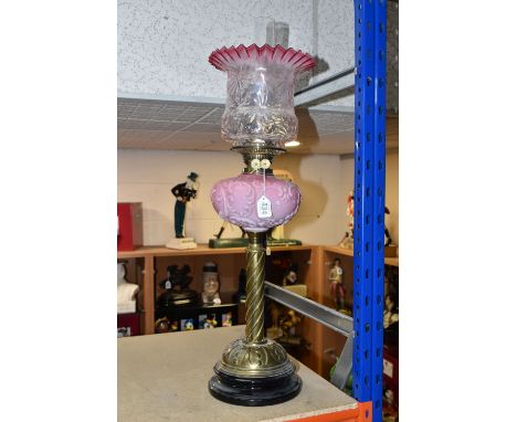A TALL VICTORIAN BRASS OIL LAMP, with a pink glass reservoir, clear to cranberry frilled shade, Duplex mechanism, rope twist 