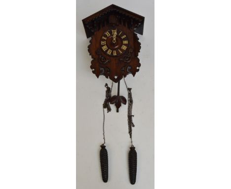 A late 19th century cuckoo clock with peaked roof, applied wooden decoration to pierced front, the circular chapter ring set 
