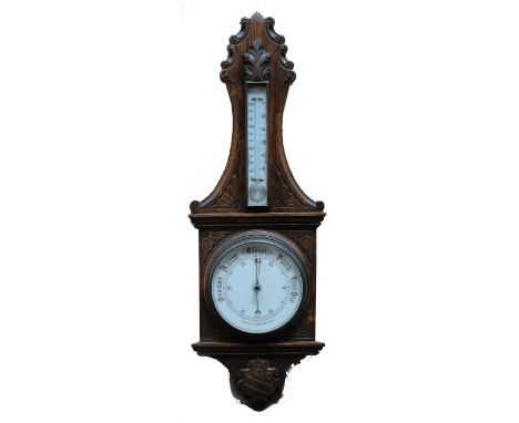 An early 20th century oak aneroid barometer/thermometer, with carved shield and foliate scroll decoration, height 90cm.