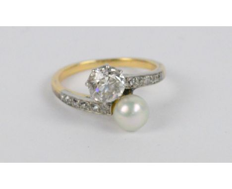 A yellow and white metal dress ring with an approx 0.5cts brilliant cut diamond and a pearl in a crossover setting, the shoul