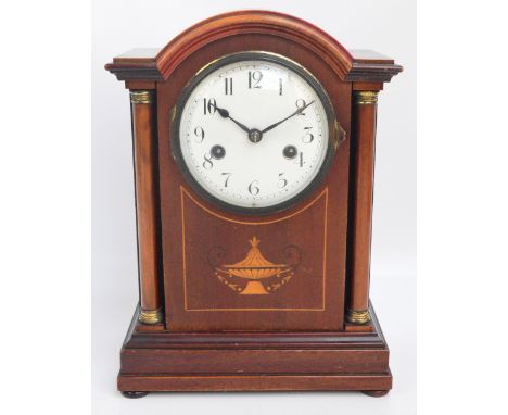 An early 20th century mahogany and inlaid eight day mantel clock with white enamel dial set with Roman numerals, on bun feet.