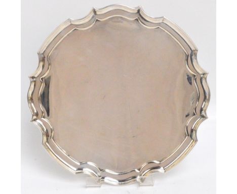 A George V hallmarked silver shaped circular salver raised on four scrolling supports, James Dixon & Son, Sheffield 1933, dia