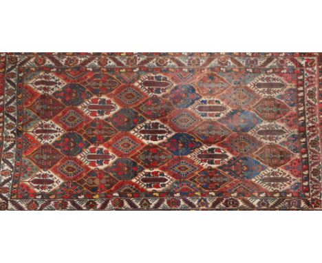 A Persian Bakhtiari carpet with lozenge motifs on a red ground, 295 x 220cm.