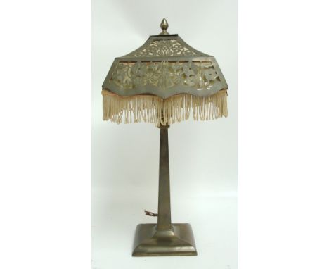 An early 20th century brass (probably railway) table lamp with square section floral pierced shade above spreading stem and b