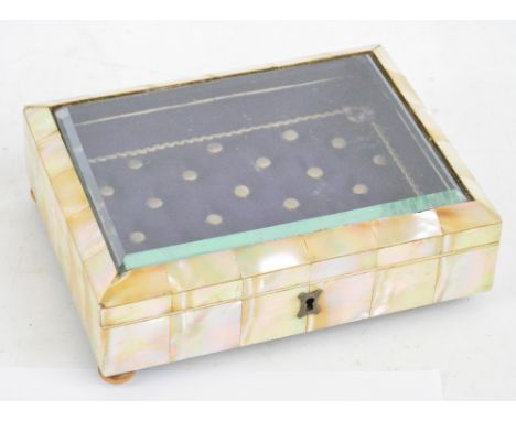 A mother of pearl faced trinket box with bevelled glass to the hinged lid enclosing a quilted interior to bun feet (one missi