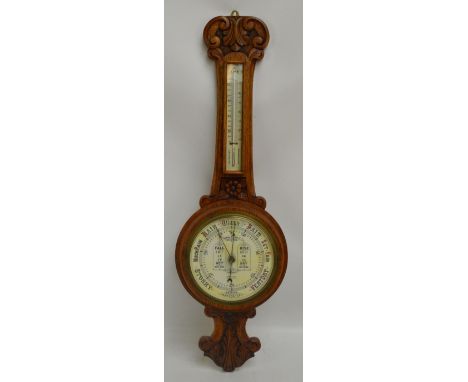 A 1930s carved oak banjo aneroid barometer/thermometer with floral and foliate scroll motifs, height 84cm.