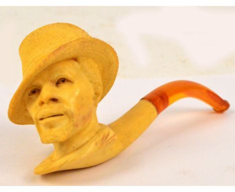 A cased pipe modelled as a man wearing a hat with amber coloured mouthpiece.
