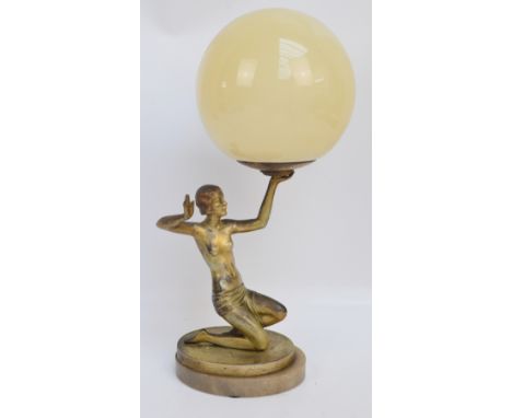 An early 20th century Art Deco painted spelter figural lamp modelled as a kneeling female nude supporting a globular white op