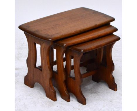A nest of three oak Ercol occasional tables with shaped trestle supports, width of largest 57cm.