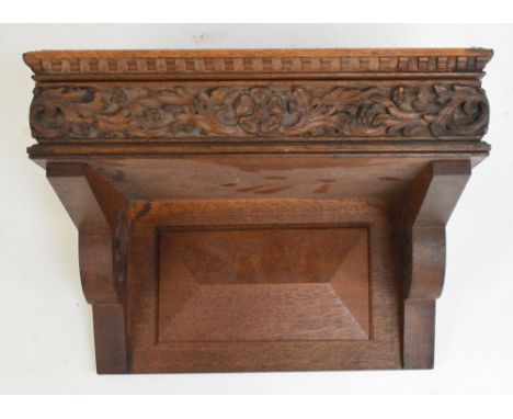 A Victorian oak bracket for a clock, the floral and leaf carved frieze flanked by Gothic quatrefoil pierced sides beneath a d