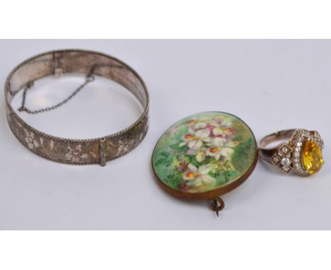 A hallmarked silver snap bangle with bright cut floral decoration, a large dress ring with pear shaped stone surrounded by cl