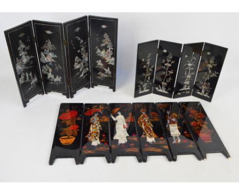 An Oriental black lacquered three fold four panel table screen set with a mother of pearl decoration of figures in a landscap
