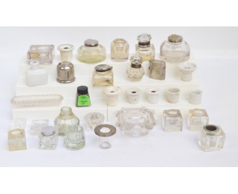 A collection of various predominantly clear glass inkwells, two travelling examples and a ceramic example with pen rest, also