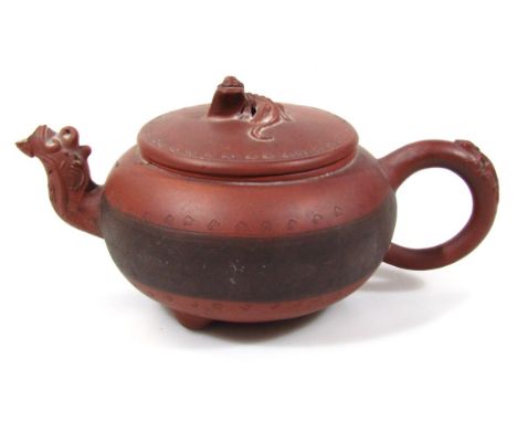 A Qing period Chinese red ware pottery teapot, of compressed bullet shape outline, with lizard knop, partial floral 'C' scrol