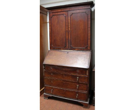 An early 19thC north country oak and mahogany crossbanded bureau bookcase, the associated top with a moulded cornice above tw