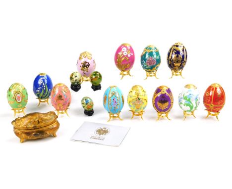 Twelve House Of Faberge replica enamel eggs, on stands, three Chinese glass eggs, painted with birds and blossom and an Art N