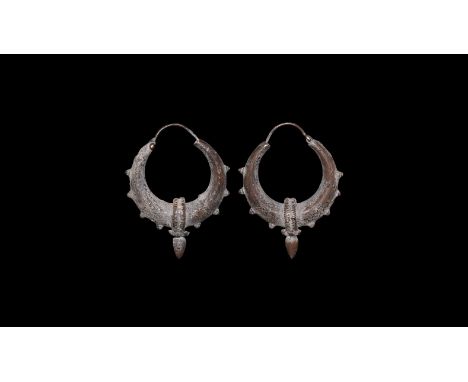 2nd millennium BC. A matched pair of silver earrings each a hollow crescentic body with radiating knops to the outer edge, ve