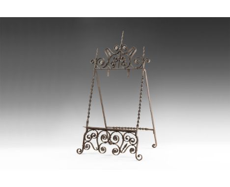 16th-17th century AD. A wrought iron stand with corkscrew frame to the sides, to the top scrolling plant motif with applied r