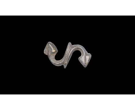 1st-2nd century AD. A bronze brooch in the form of an S with central rib and arrow shaped heads; pin hinge and catch plate to