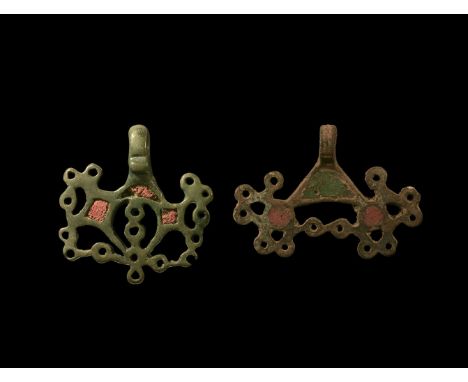 3rd-5th century AD. A pair of Kiev culture bronze pendants comprising: one with two discs with six radiating lobes, red ename
