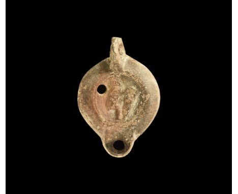 Late 2nd-early 3rd century AD. A broad terracotta oil lamp with dimpled discoid base, broad shoulder, short D-shaped nozzle, 