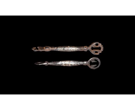 9th-11th century AD. A group of two iron keys comprising: one with balustered shank, pierced flange finial, D-shaped head wit
