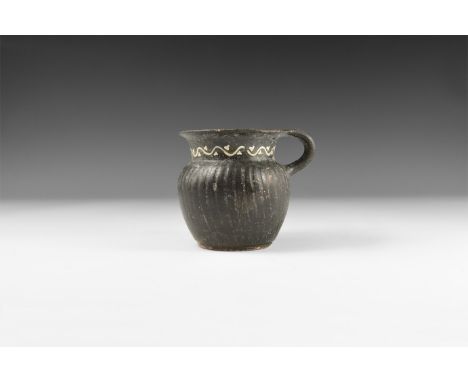 5th-3rd century AD. A ceramic blackware vessel with broad neck and narrow flared rim, vertical ribbing to the body, vinescrol