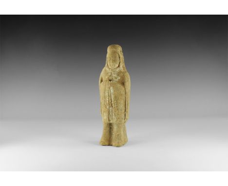 Northern Qi Dynasty, 550-577 AD. A terracotta figure of a standing attendant in hood and tunic with bell sleeves, hands drawn