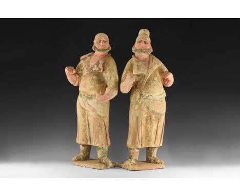 Tang Dynasty, 618-906 AD. A pair of large ceramic figures of foreign grooms with pigment, one facing left, the other facing r