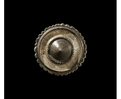 2nd century AD. A tinned discoid plate brooch with dentilled edge, raised rim, silvered band, beaded rim and central cone; pi