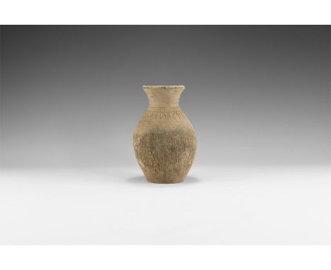 3rd millennium BC. A terracotta biconical jar with broad flared rim, leather texture to the body and hatched grid to the shou