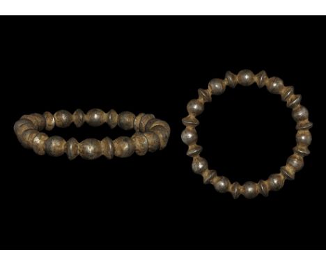 5th-4th century BC. A round-section hollow silver bangle formed as alternating bulbs and biconical plates.   42 grams, 78mm (