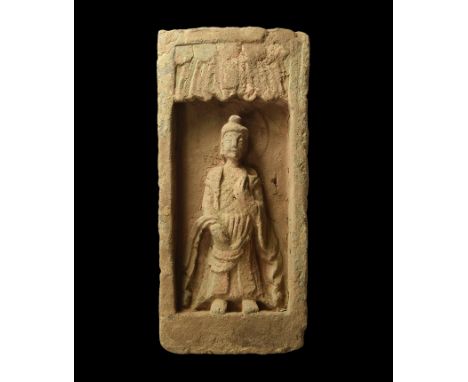 Northern Wei Dynasty, 386-534 AD. A rectangular grey ceramic brick with recess to the upper face enclosing a robed Buddha fig